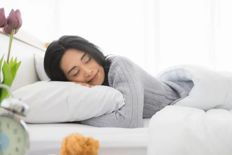 Person resting comfortably on their side in bed, illustrating side-sleeping for reduced airway collapse